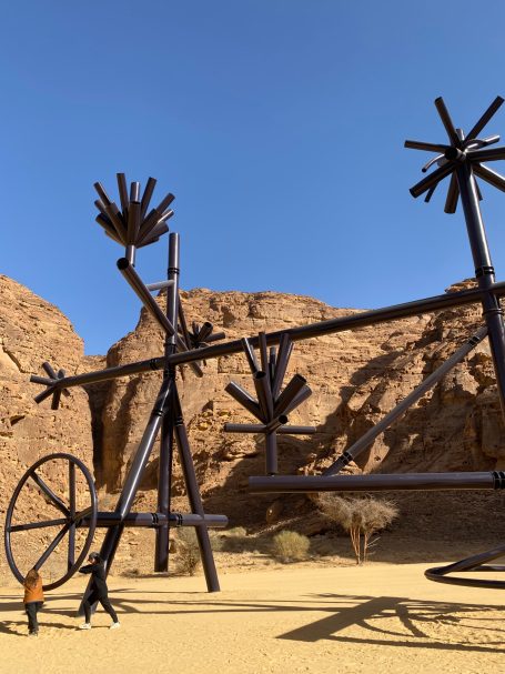 Große Metallskulptur in einer Wüstenlandschaft mit künstlerischen Details und Schatten.