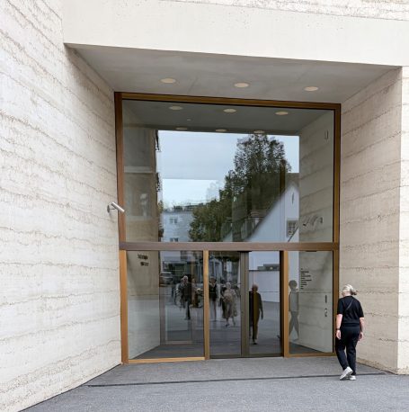 Tiefes Portal in heller Fassade mit holzgerahmten Glastüren