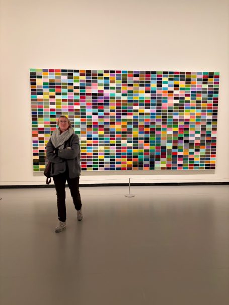 Eine Person geht vor einem bunten Kunstwerk mit vielen Farbfeldern.