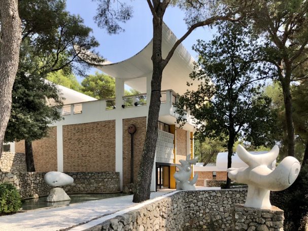 Moderne Architektur umgeben von Bäumen und Skulpturen im Freien.