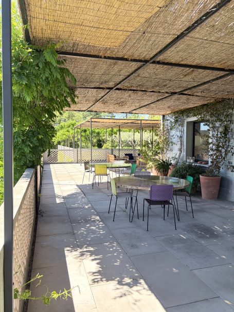 Geräumige Terrasse mit bunten Stühlen, Pflanzen und Sonnenschutzdach.