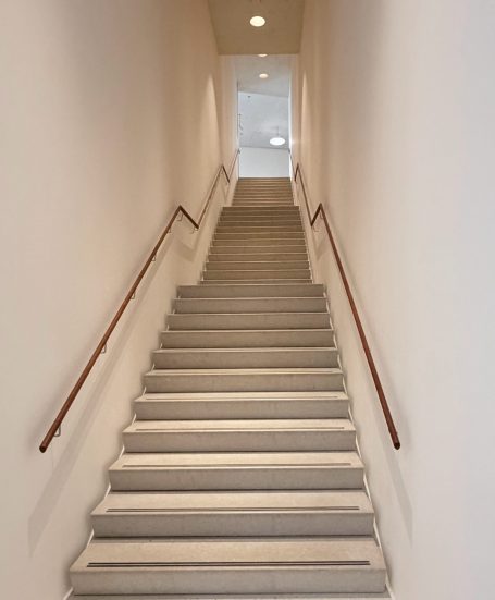 Schmale helle Treppe mit Holzhandläufen links und rechts