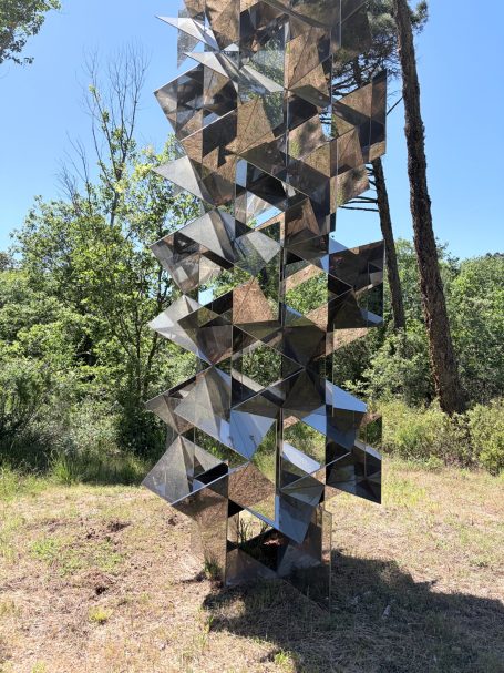 Skulptur aus spiegelndem Material, bestehend aus stilisierten, quadratischen Elementen.