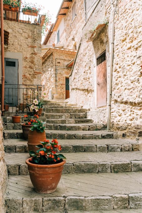 Enge Gasse mit steinernen Treppen und blühenden Töpfen aus Terrakotta.