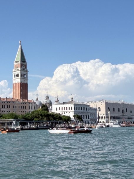 Der Markusplatz in Venedig mit dem Campanile und Boote im Wasser.