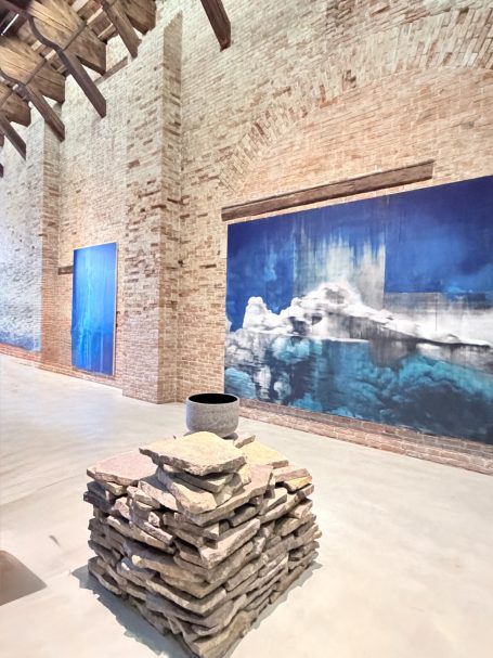 Moderne Galerie mit blauen Wandbildern und einem Steinhaufen in der Mitte.