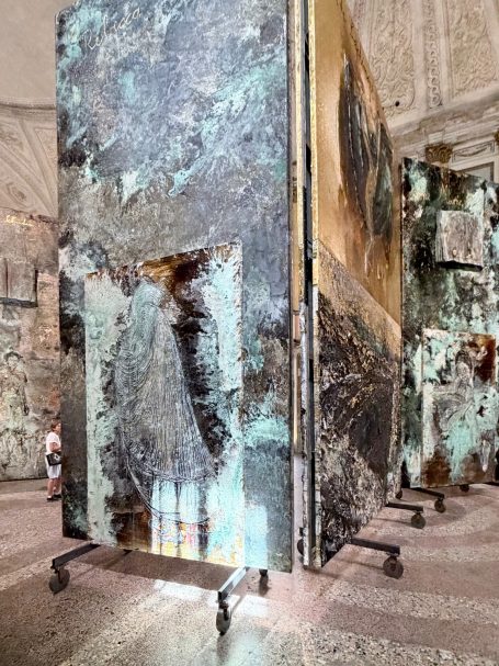 Moderne Skulpturen in einem historischen Innenraum, mit reflektierenden Oberflächen. Mit Besucher im Hintergrund