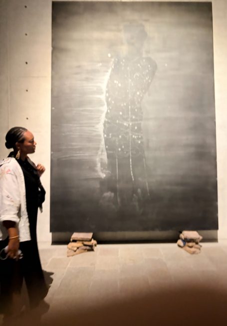 Person betrachtet ein großes, künstlerisches Wandbild in einem modernen Ausstellungsraum.
