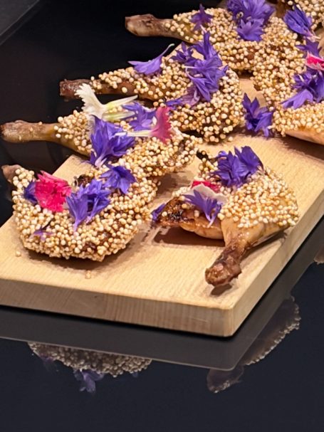 Mit Blumen und Sesam verzierrte Wachtelschenkel 
