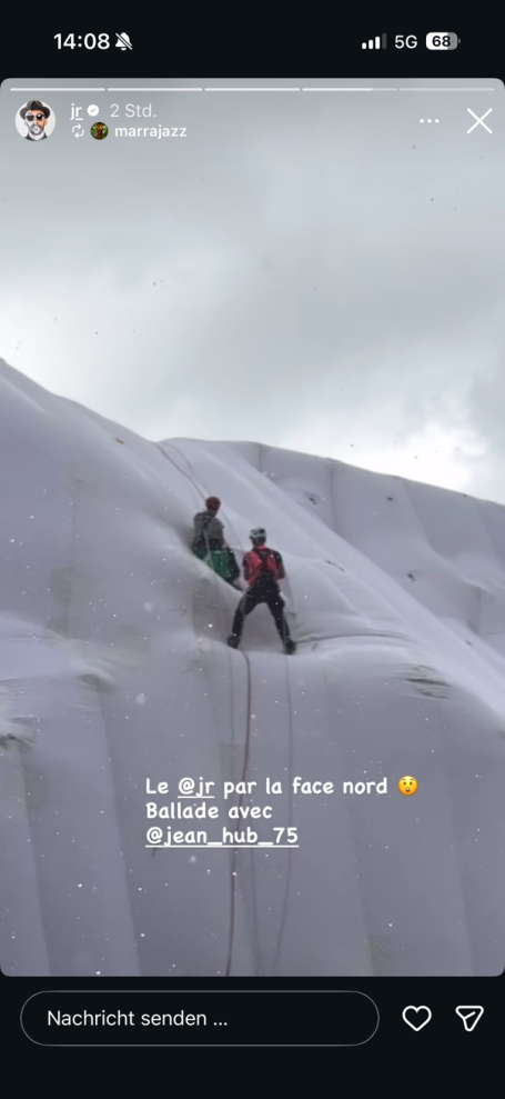 Zwei Personen klettern auf einer schneebedeckten Fläche unter grauem Himmel.