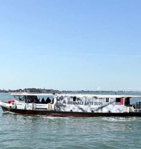 Schiff mit grauer Bemalung fährt auf ruhigem Wasser unter blauem Himmel.