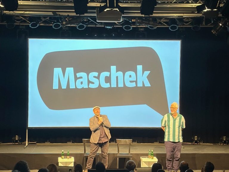 Zwei Männer stehen auf einer Bühne, im Hintergrund das Wort „Maschek“ in einer Sprechblase.