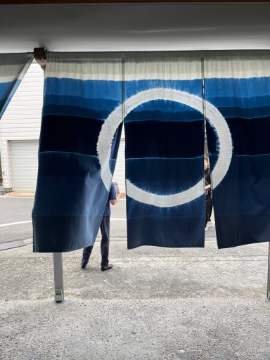 Blau-weiße Vorhänge mit einem großen, weißen Kreis in der Mitte, auf einem Gehweg.