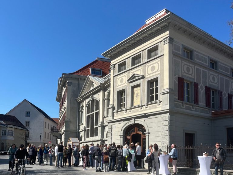 Kunstwerk aus grünen Glasfragmenten hängt in einer Kirche.