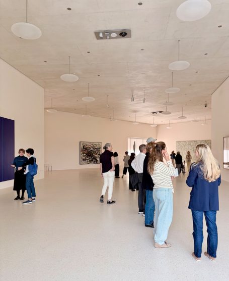 Großer Saal mit runden Deckenleuchten und Besuchern