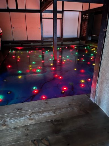 Bunte Lichter spiegeln sich im Wasser eines abgedunkelten Raumes.