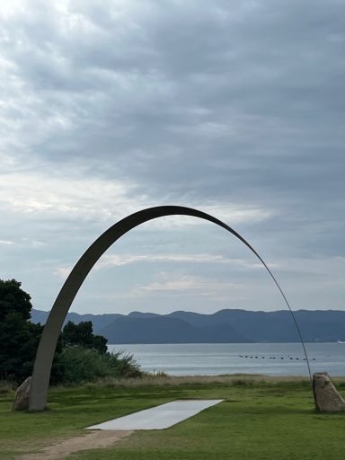 Sichtbare Bogenstruktur neben einem Gewässer unter bewölktem Himmel.