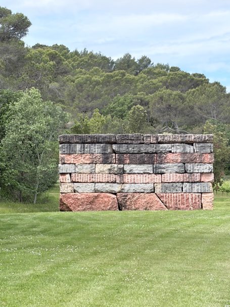 Farbenfrohes, gestapeltes Steinformationen in einer grünen Landschaft mit Bäumen im Hintergrund.