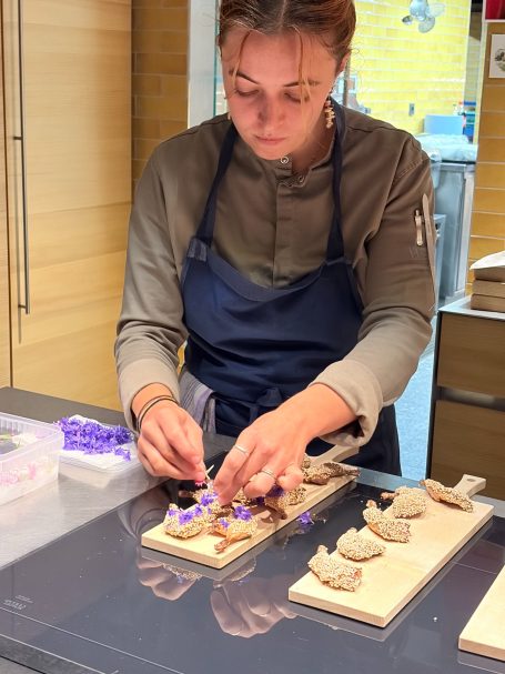Junge Frau bereitet Speise auf einem Holzbrett