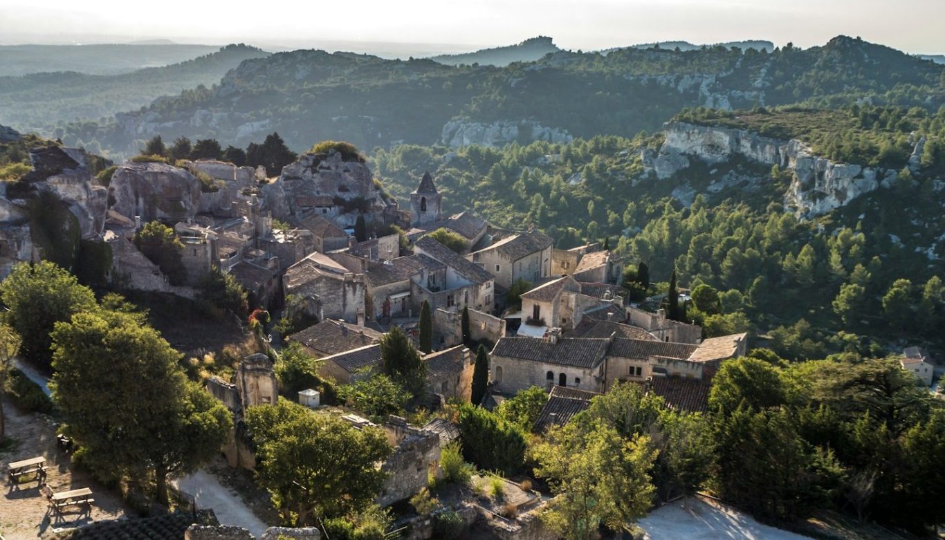 Blick auf eine malerische Landschaft mit einem historischen Dorf und umliegenden Hügeln.
