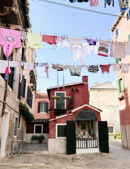 Bunte Wäsche hängt zwischen Gebäuden in einer ruhigen italienischen Gasse.