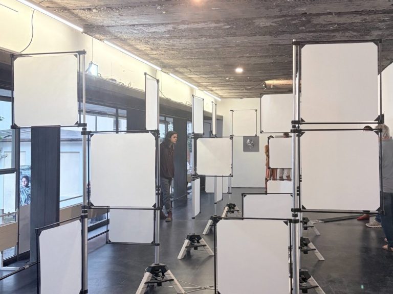 Installation aus mehreren weißen Paneelen, die auf Ständern in einem Raum angeordnet sind.