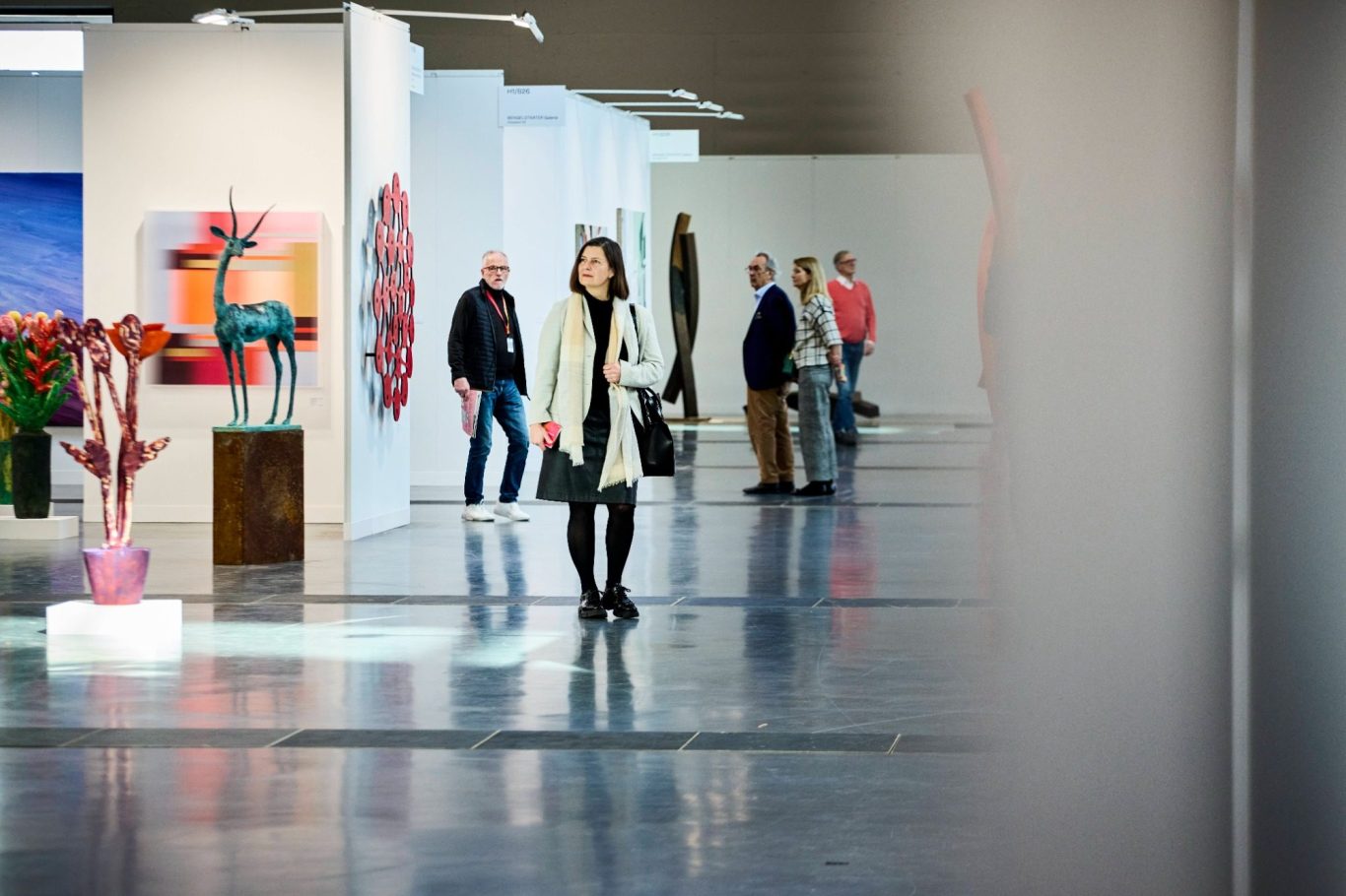 Besucher einer Kunstausstellung in einer modernen Galerie mit Skulpturen und Kunstwerken.