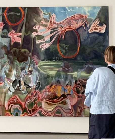 Eine Person betrachtet ein abstraktes Gemälde mit lebhaften Farben und surrealen Motiven.