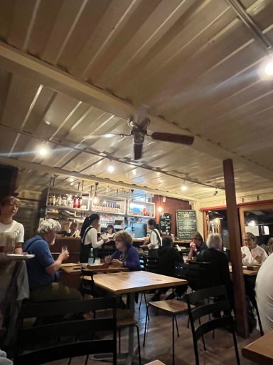 Gemütliches Restaurant mit Holzdecken, Tischen und Gästen bei einem Essen.