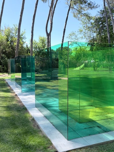 Bunte, transparente Kunststoffpaneele in einem Garten mit Bäumen im Hintergrund.